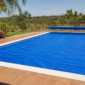 Piscina residencial coberta com capa térmica azul e enrolador ao fundo