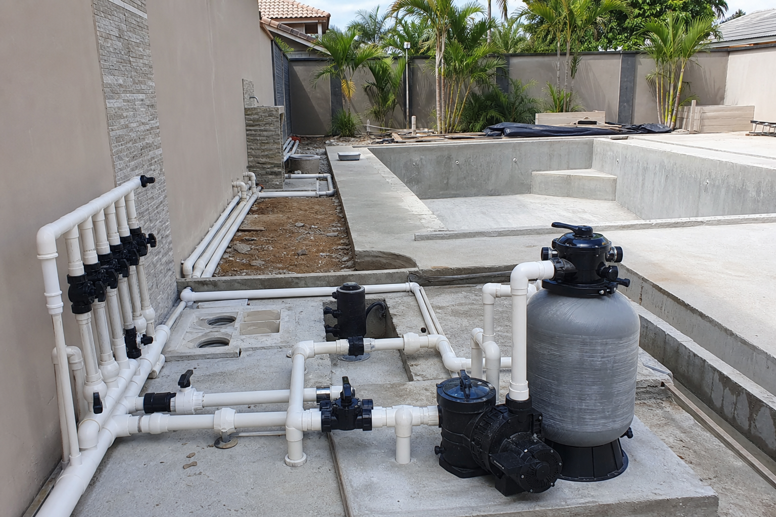Sistema de bomba, filtro e tubulações instalado ao lado de piscina ainda em obra