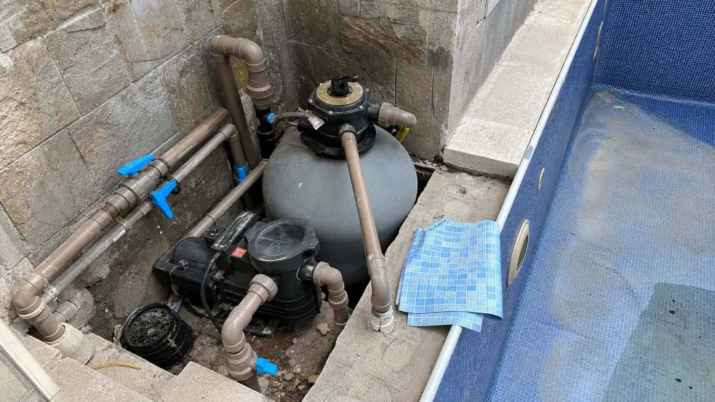 Filtro de areia bomba tubulações e amostra de vinil azul ao lado de piscina durante inspeção de reforma