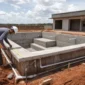 Piscina em obra com estrutura de alvenaria concreto tubulações hidráulicas e técnico conferindo medidas