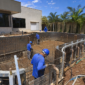 Obra de piscina residencial com estrutura armada tubulações e equipe técnica trabalhando em Goiânia