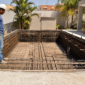 Piscina em construção com ferragens, pontos hidráulicos e técnico avaliando a estrutura antes da concretagem