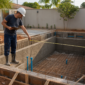 Técnico medindo estrutura de piscina em construção com ferragens e tubulações no Jardim Maria Inês em Aparecida de Goiânia