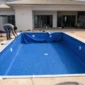 Técnico medindo borda de piscina de vinil azul em construção com dispositivos hidráulicos visíveis