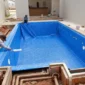 Equipe instalando vinil azul e pontos hidráulicos em piscina residencial em obra