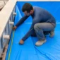 Técnico medindo vinil azul e dispositivos hidráulicos em piscina residencial em construção