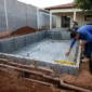 Técnico medindo estrutura de piscina em construção com ferragens e tubulação hidráulica aparente