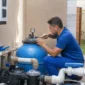 Técnico verificando filtro de areia manômetro bomba e tubulações da casa de máquinas de piscina