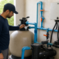 Técnico conferindo manômetro em filtro de areia e bomba de piscina residencial