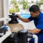 Técnico verificando filtro de areia manômetro bomba e tubulações da casa de máquinas de piscina residencial