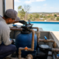Técnico verificando filtro de areia bomba tubulação válvulas e manômetro ao lado de piscina residencial