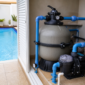 Filtro de areia e bomba de piscina instalados em casa de máquinas ao lado de piscina residencial