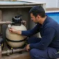 Técnico verificando manômetro, bomba e filtro de areia ao lado de piscina residencial