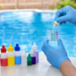 Técnico com luvas usando reagente e comparador para medir alcalinidade e pH da água da piscina