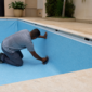 Técnico instalando revestimento vinílico azul em piscina vazia no Aeroviário em Goiânia