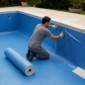 Técnico instalando revestimento vinílico azul em piscina residencial para troca de vinil em Aparecida de Goiânia