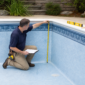 Técnico medindo parede de piscina com revestimento vinílico azul para troca de vinil no Jardim América em Goiânia