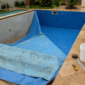 Piscina residencial com vinil antigo removido e novo vinil azul sendo posicionado para troca