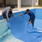 Técnicos medindo e posicionando novo vinil azul durante reforma de piscina residencial em Goiás