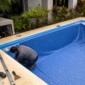 Técnico instalando revestimento vinílico azul em piscina residencial durante reforma em Goiânia