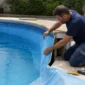 Técnico inspecionando vinil de piscina parcialmente solto durante avaliação para troca do revestimento