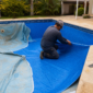 Técnico instalando vinil azul novo em piscina residencial durante troca do revestimento