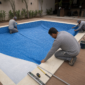 Equipe posicionando manta de vinil azul em piscina residencial durante reforma em Goiânia
