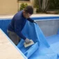 Técnico posicionando manta de vinil azul durante troca de revestimento de piscina