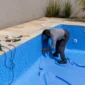 Técnico instalando revestimento vinílico azul em piscina residencial durante reforma no Setor Garavelo em Aparecida de Goiânia
