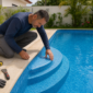 Técnico inspecionando vinil de piscina enrugado nos degraus
