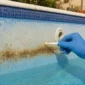 Vinil de piscina azul manchado com teste de água ao lado da parede da piscina