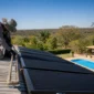Técnico instalando coletores de aquecimento solar em telhado com piscina residencial ao fundo
