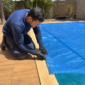 Técnico verificando capa térmica sobre piscina residencial
