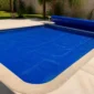 Capa térmica azul de bolhas instalada sobre piscina residencial em Nova Veneza