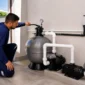 Técnico inspecionando filtro de areia, bomba e tubulação de casa de máquinas de piscina