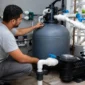 Técnico conferindo manômetro em filtro de areia com bomba e tubulação de piscina residencial