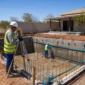 Técnicos nivelando estrutura de piscina em construção com tubulação hidráulica aparente