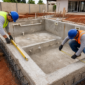 Piscina de alvenaria em construção com técnicos conferindo nível, medidas e tubulações em Campo Limpo de Goiás