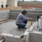 Piscina de alvenaria em construção com técnico conferindo nível, medidas e tubulações em Carmo do Rio Verde