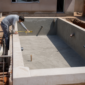 Técnico conferindo nível e tubulações em piscina residencial em construção no Jardim Tropical