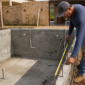 Piscina de alvenaria em construção com tubulações hidráulicas e técnico conferindo a estrutura
