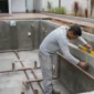 Técnico conferindo nível e tubulações em piscina residencial em construção na Vila Alzira