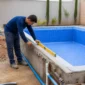 Técnico conferindo nível e tubulações em piscina residencial em construção na Vila Maria José