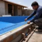 Técnico medindo piscina de vinil em construção com tubulações hidráulicas aparentes