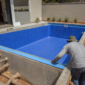 Piscina residencial de vinil em construção no Parque Atheneu com técnico conferindo medidas e tubulações hidráulicas