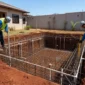 Técnicos com capacete conferindo armação de aço e tubulações durante construção de piscina residencial
