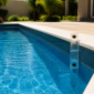 Piscina residencial com régua transparente de referência para acompanhar o nível da água e diferenciar evaporação de perda anormal.