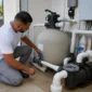 Técnico verificando filtro de areia, manômetro, bomba e tubulações da casa de máquinas de piscina no Parque Real