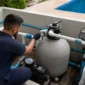 Técnico verificando manômetro em filtro de areia bomba e tubulações de casa de máquinas de piscina residencial