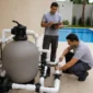 Técnicos conferindo filtro de areia, bomba e tubulação de casa de máquinas ao lado de piscina residencial